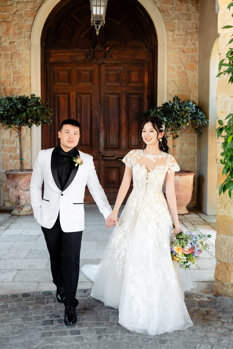 bride and groom holding hands walking together in front of the entrance door at the venue